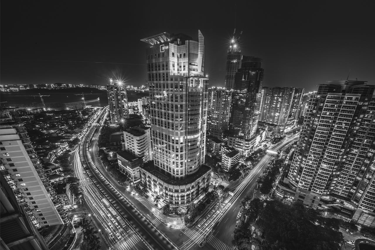 Stunning black and white image of a dynamic urban cityscape at night, showcasing architecture and bustling traffic.
